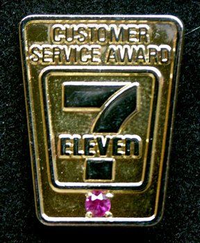 A gold pin that says customer service award eleven