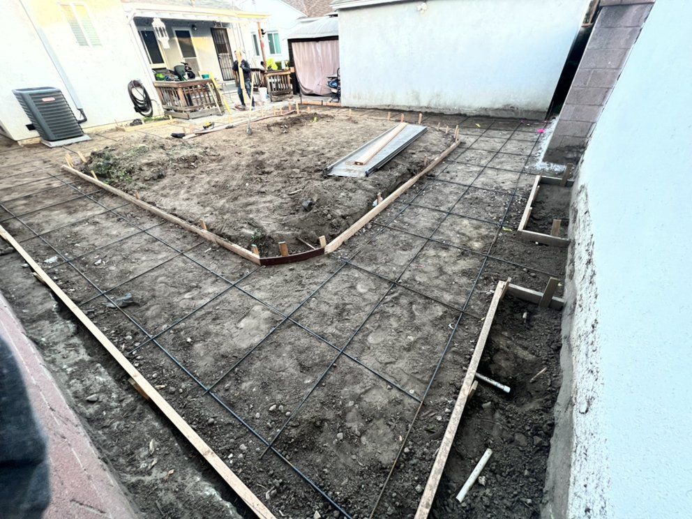 A concrete walkway is being built in the backyard of a house.