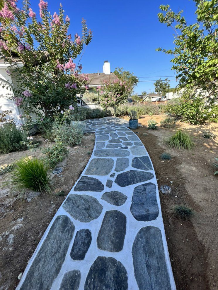 A stone walkway leading to a house in a garden.