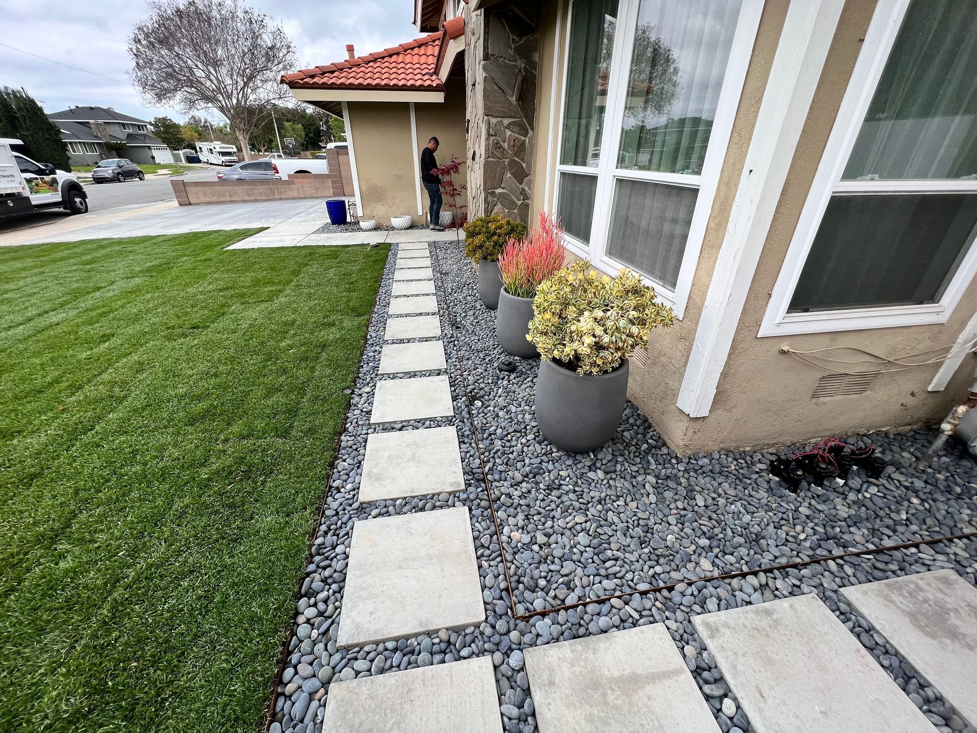 A man is working on the sidewalk in front of a house.