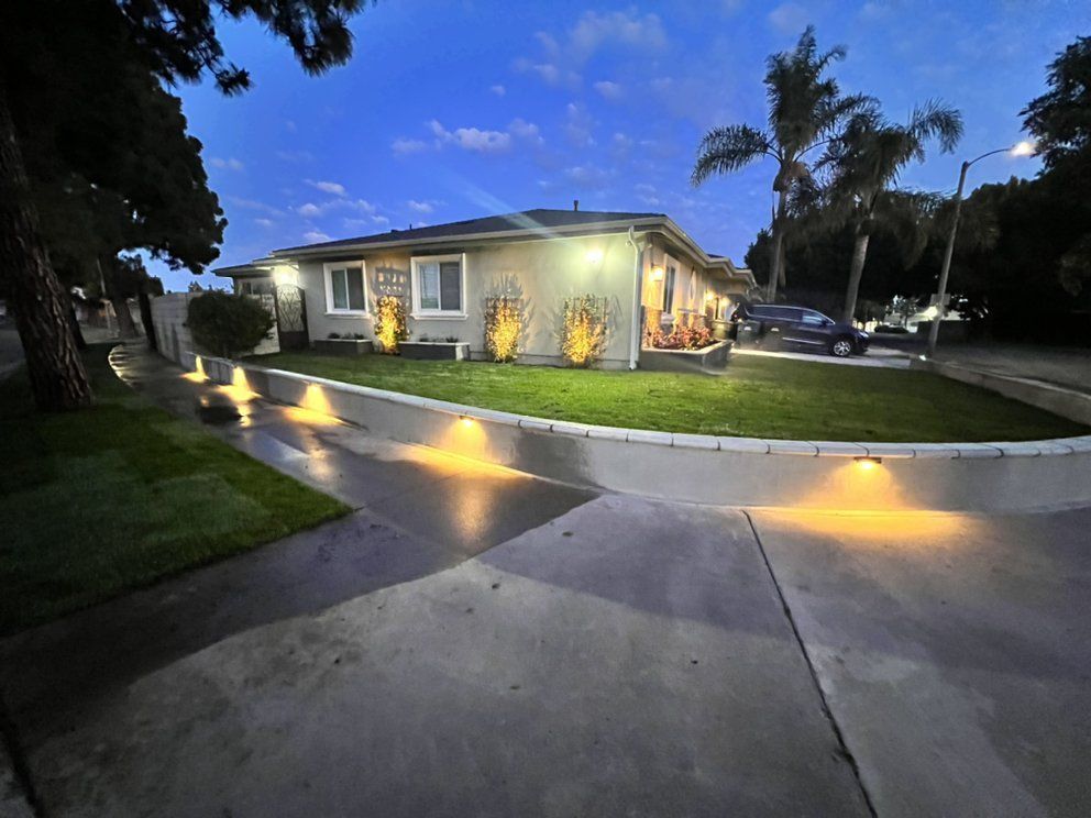 A house is lit up at night with a car parked in front of it.