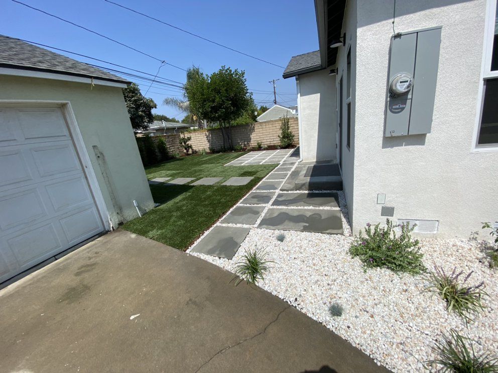 A white house with a walkway leading to it and a garage.