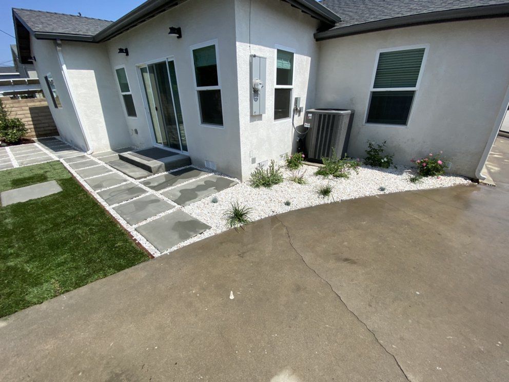 A white house with a concrete walkway leading to it.