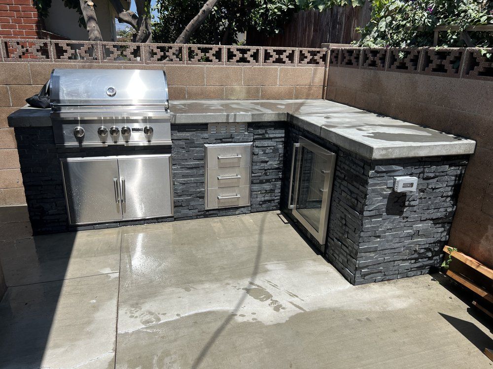 A stainless steel grill is sitting on top of a concrete patio.