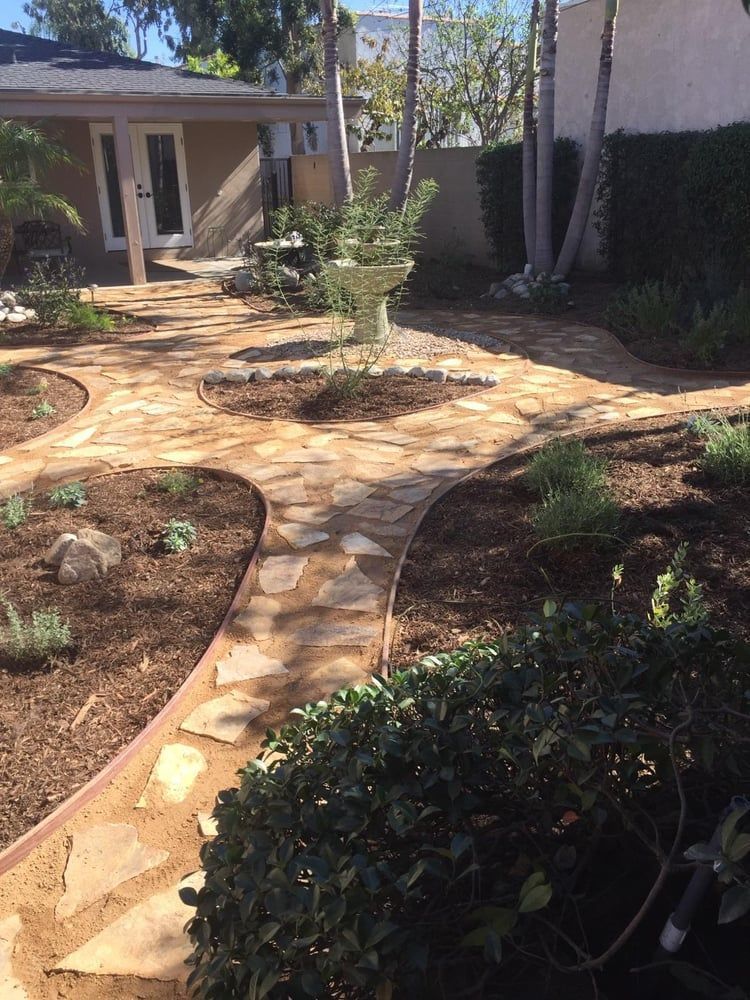 A stone walkway leading to a house in a garden.