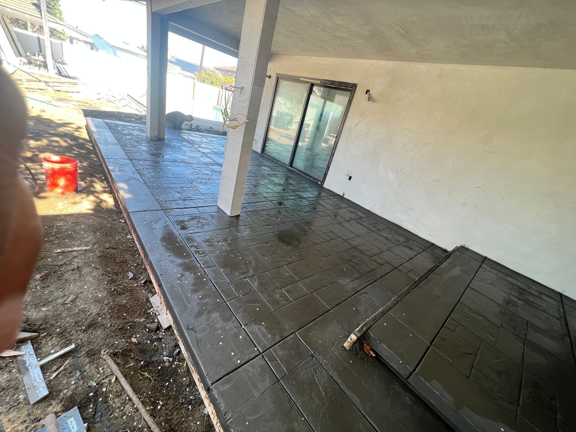 A person is standing on a concrete patio in front of a building under construction.