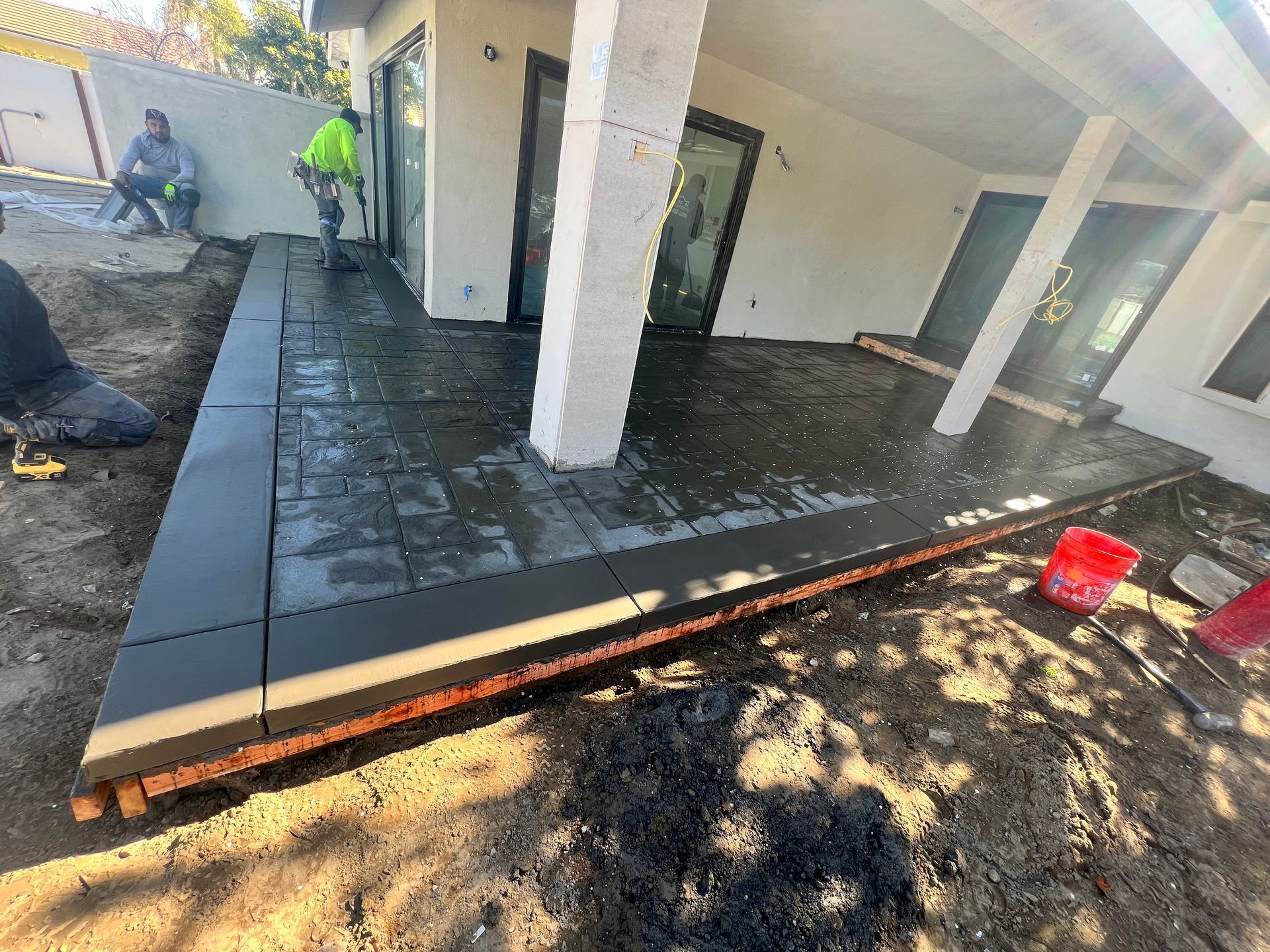 A patio is being built in the backyard of a house.