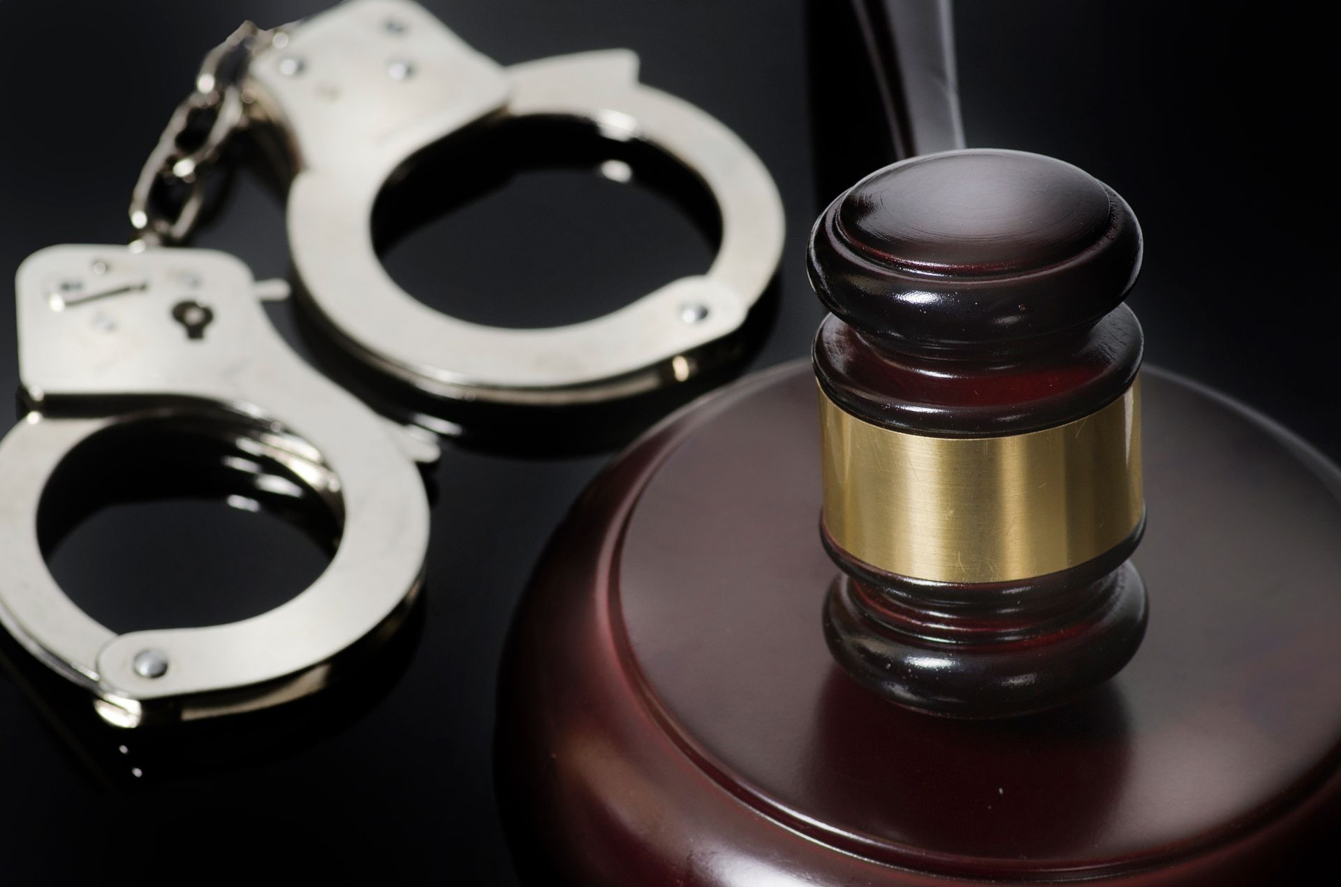 A pair of handcuffs sitting next to a judge's gavel.