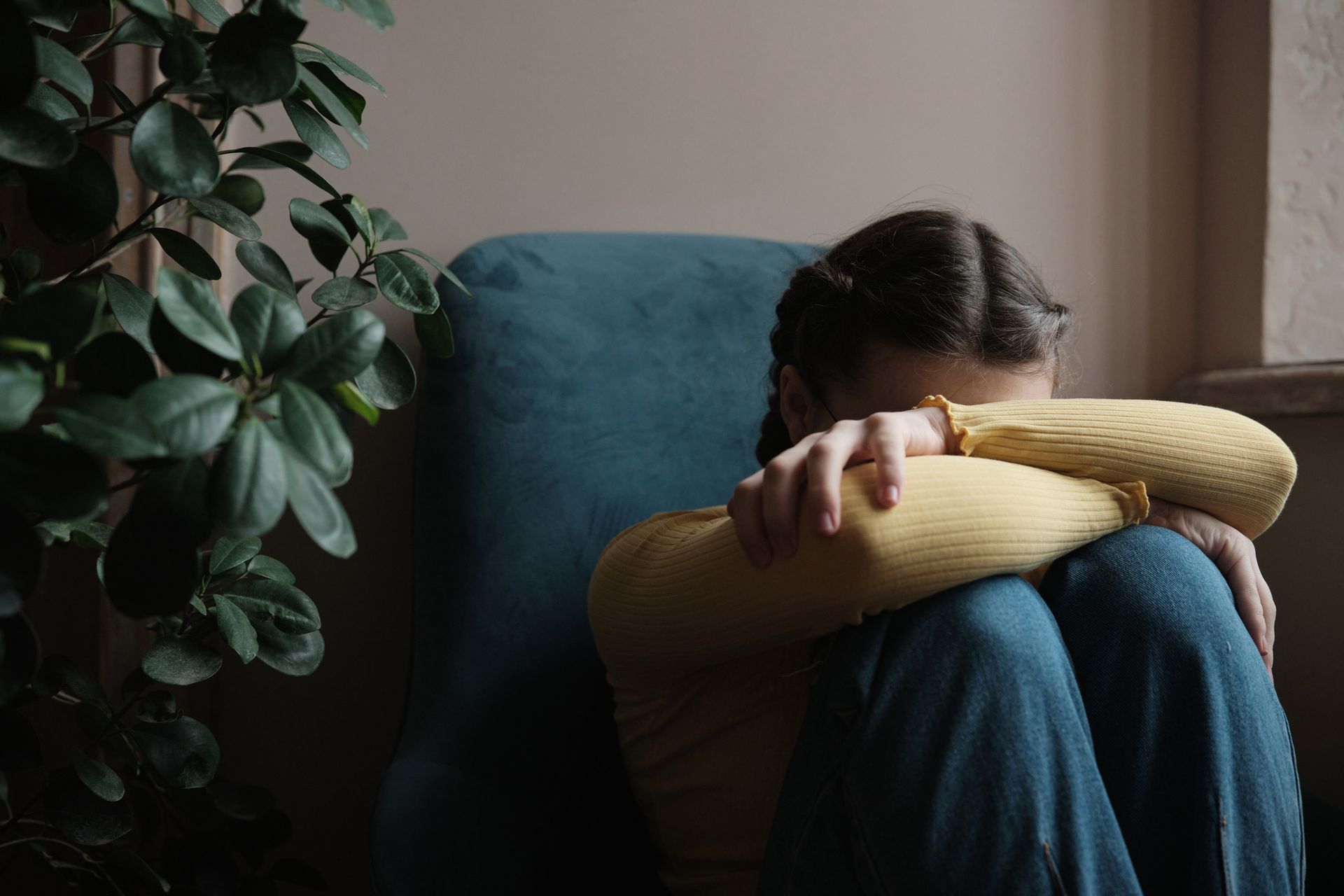 A woman is sitting in a chair with her head in her hands.