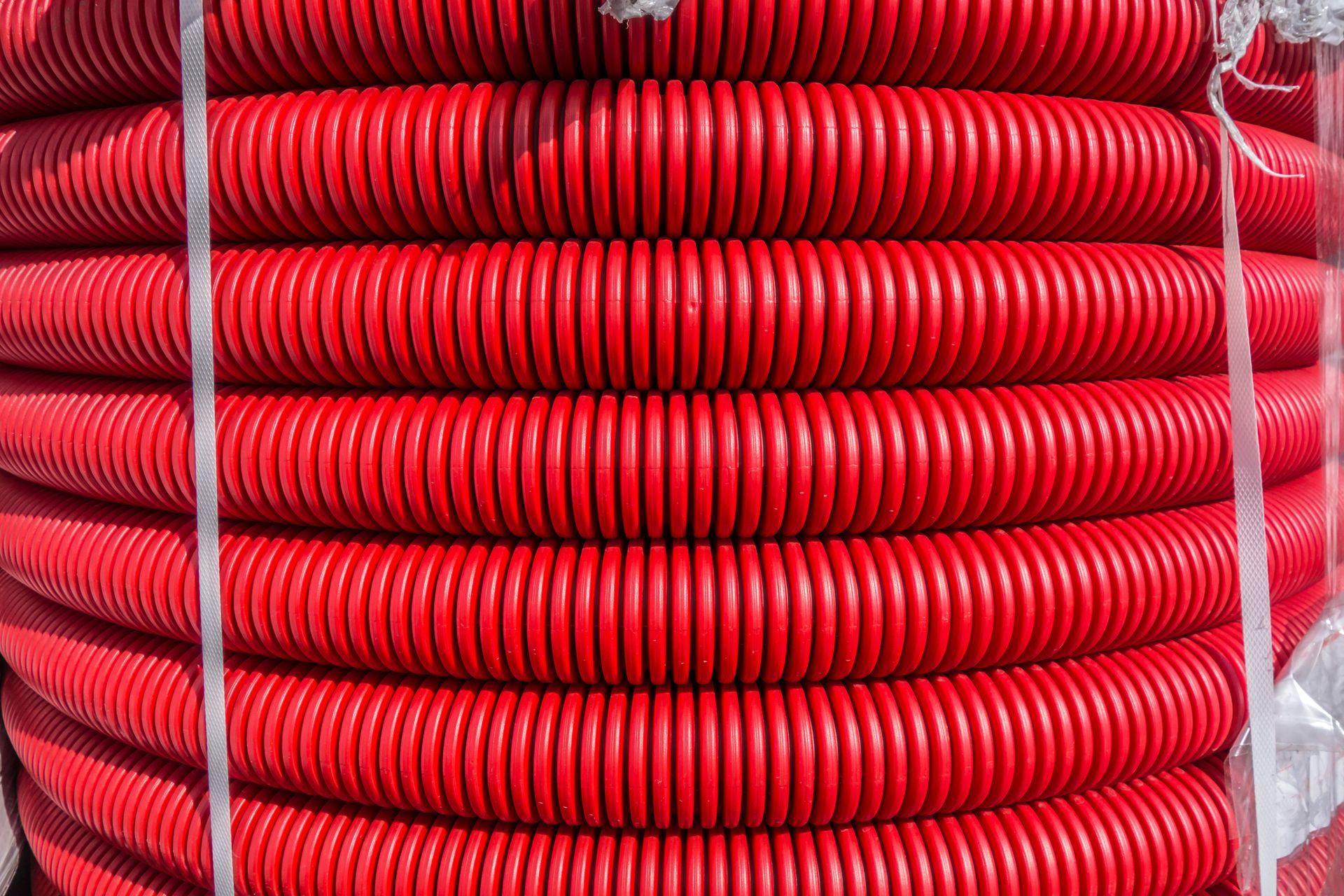 Red plastic industrial machine hose in a pile.