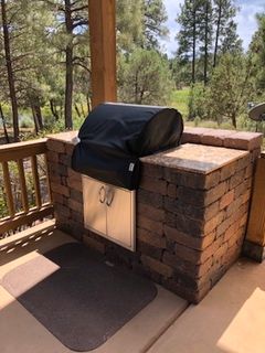 Outdoor brick barbecue with black grill cover and stainless steel doors.