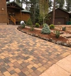Brick driveway leading to wood cabins with landscaping.