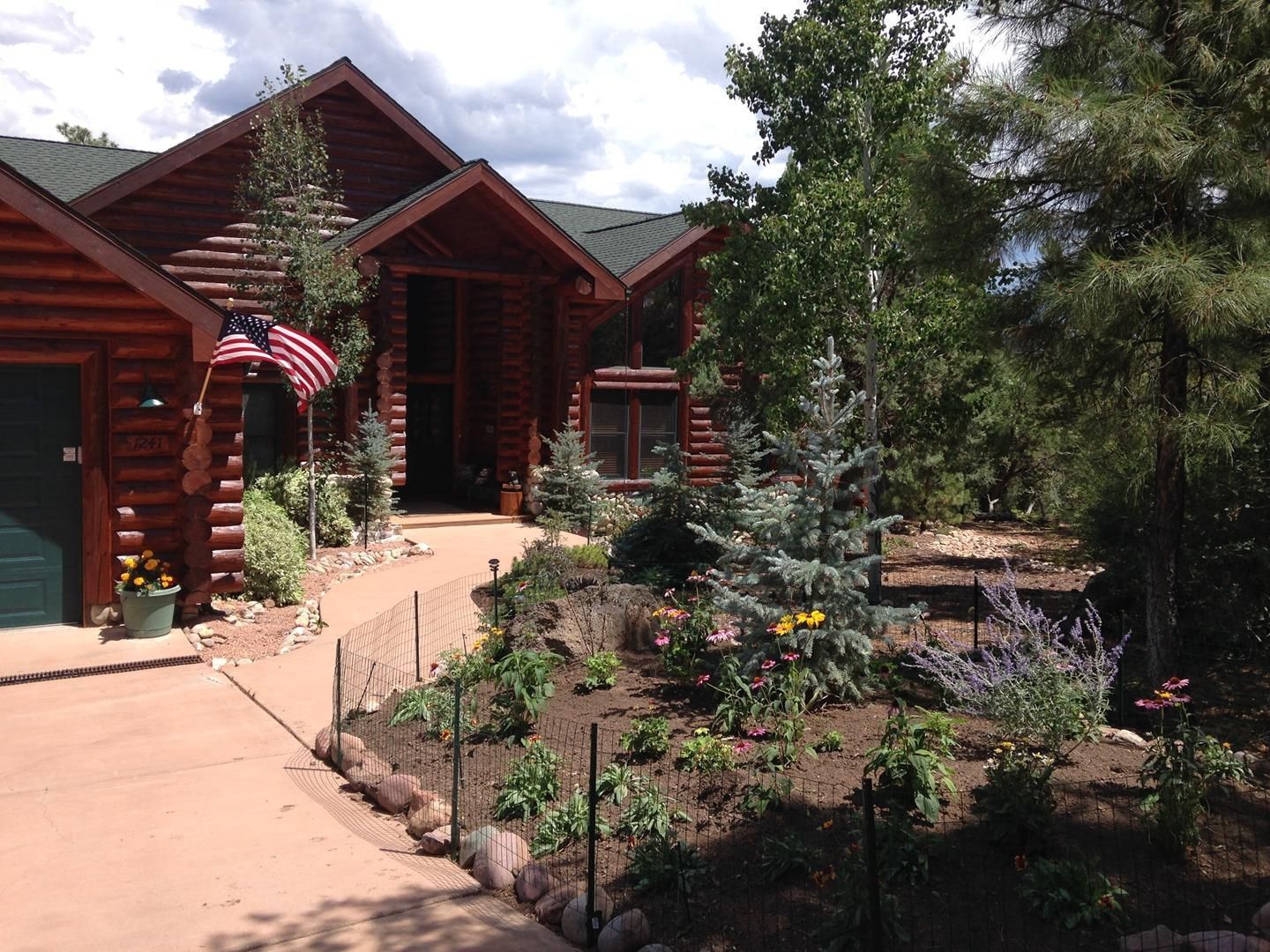 Log cabin home with a landscaped front yard and American flag.
