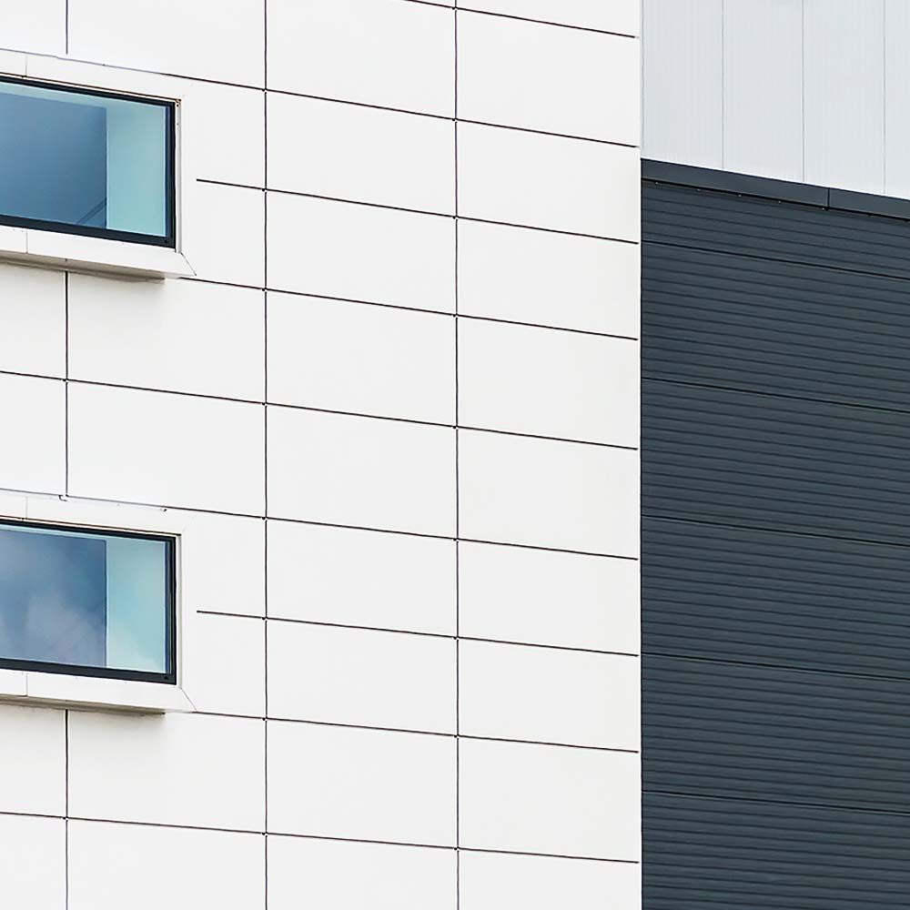 White and grey modern building exterior with two windows.