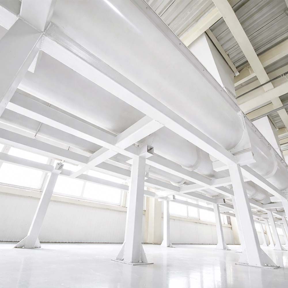 White industrial pipes and support structure in a bright, spacious room.