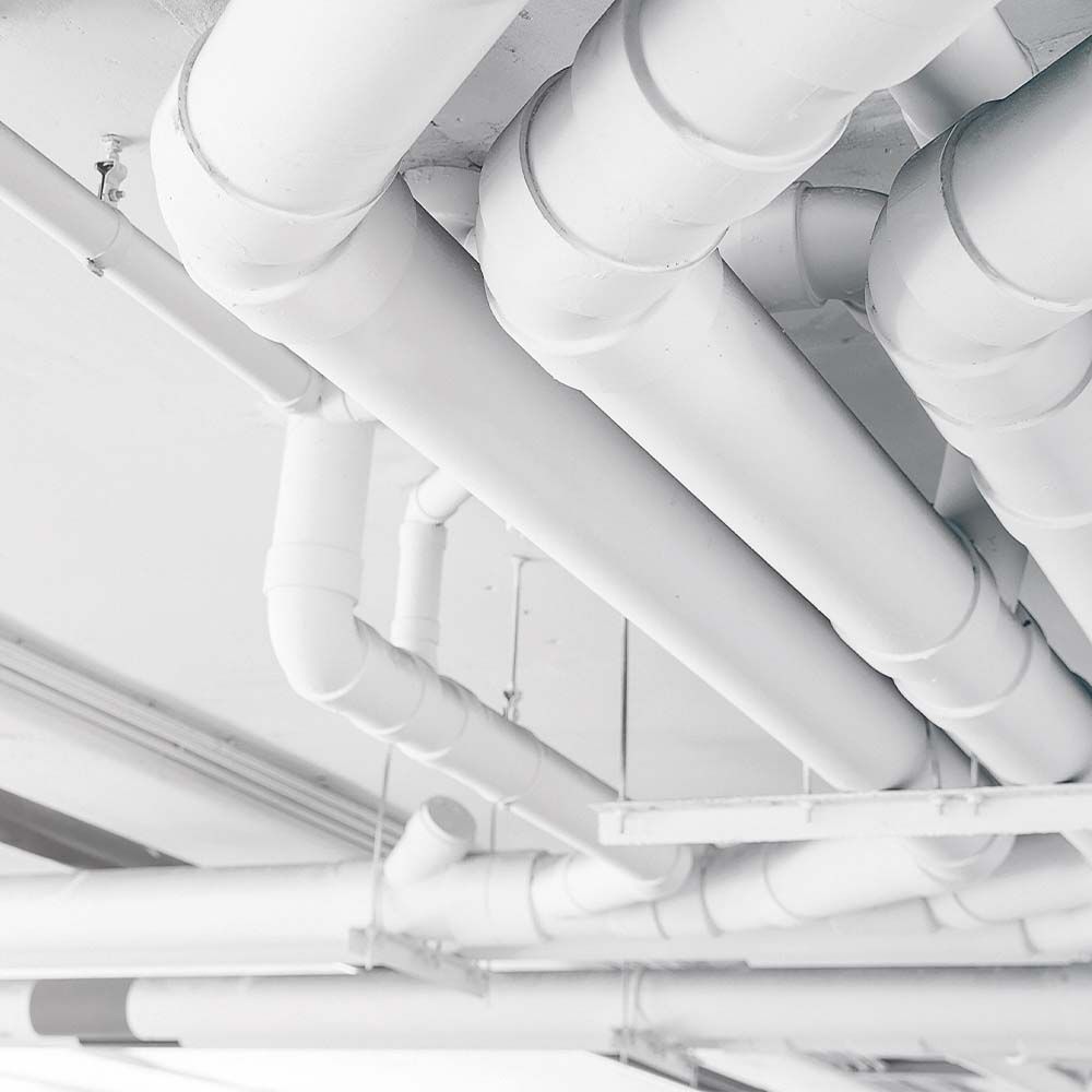 White pipes and fittings attached to a white ceiling.