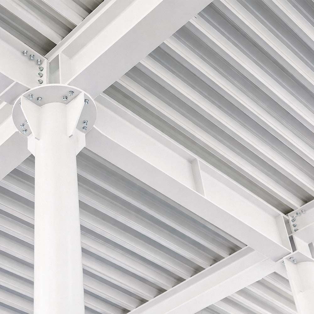 White steel beams and corrugated ceiling in an industrial building interior.