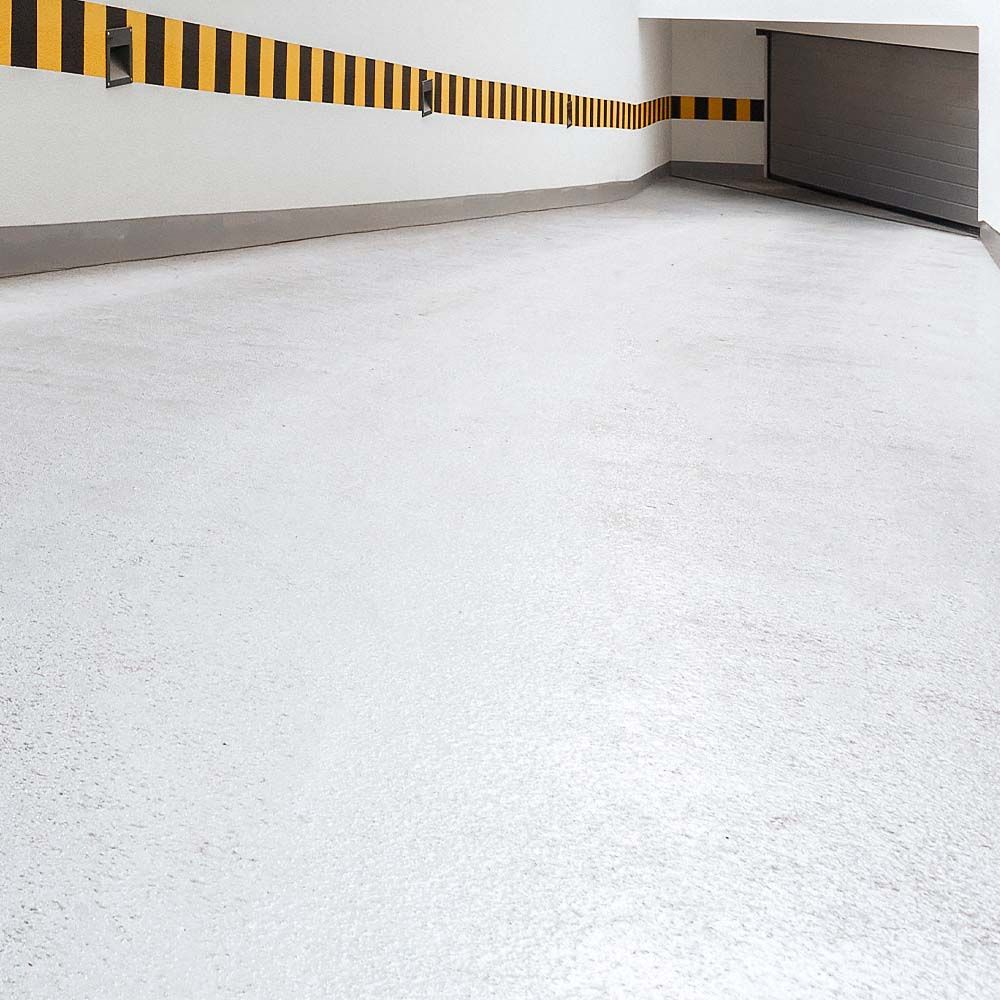 White concrete garage floor with yellow and black safety stripes.