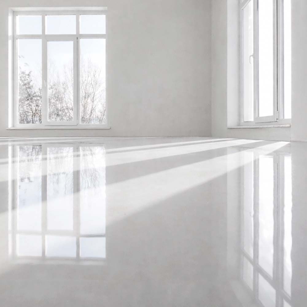 Empty, bright room with glossy white floor, two windows, and white walls reflecting light.