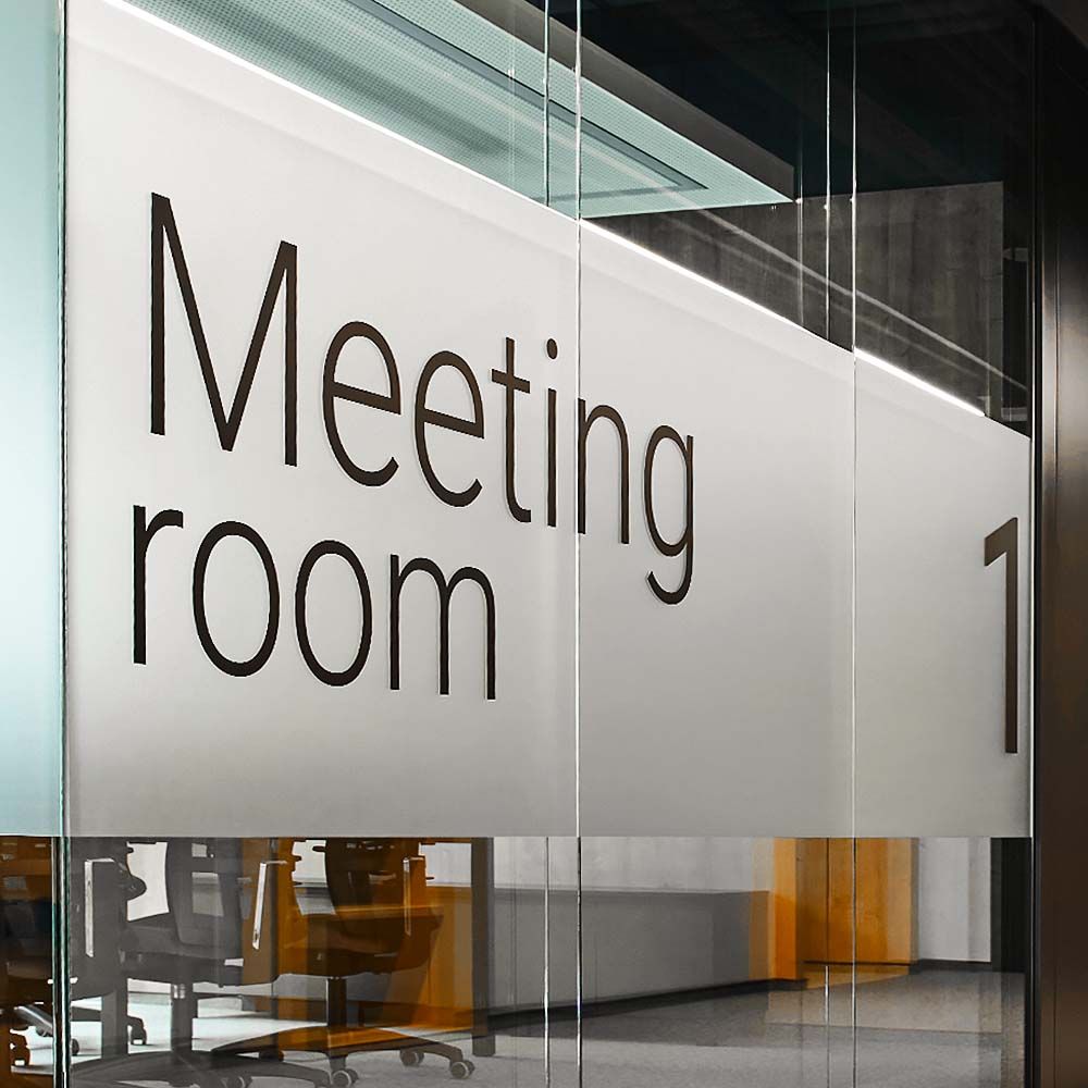 Glass wall with meeting room vinyl wrap signage inside modern office interior