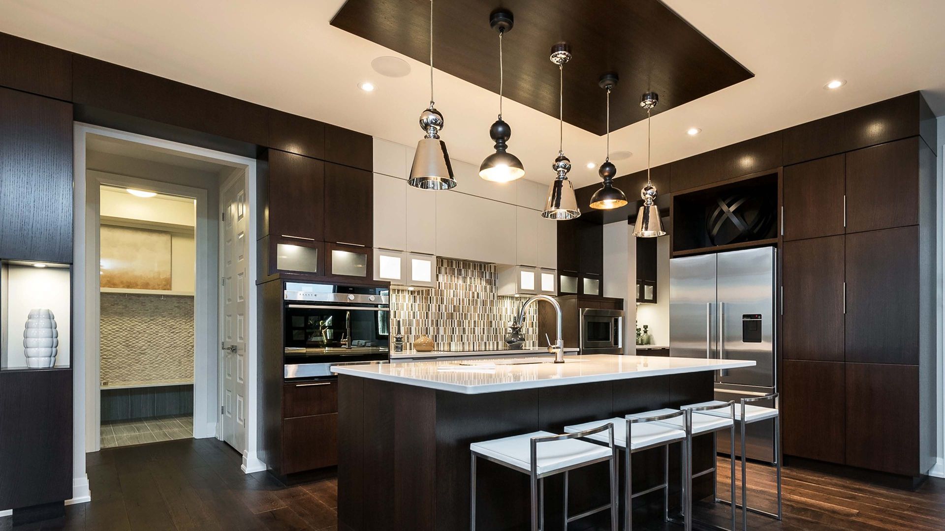 Modern kitchen with dark cabinetry, stainless steel appliances, and island with pendant lights.