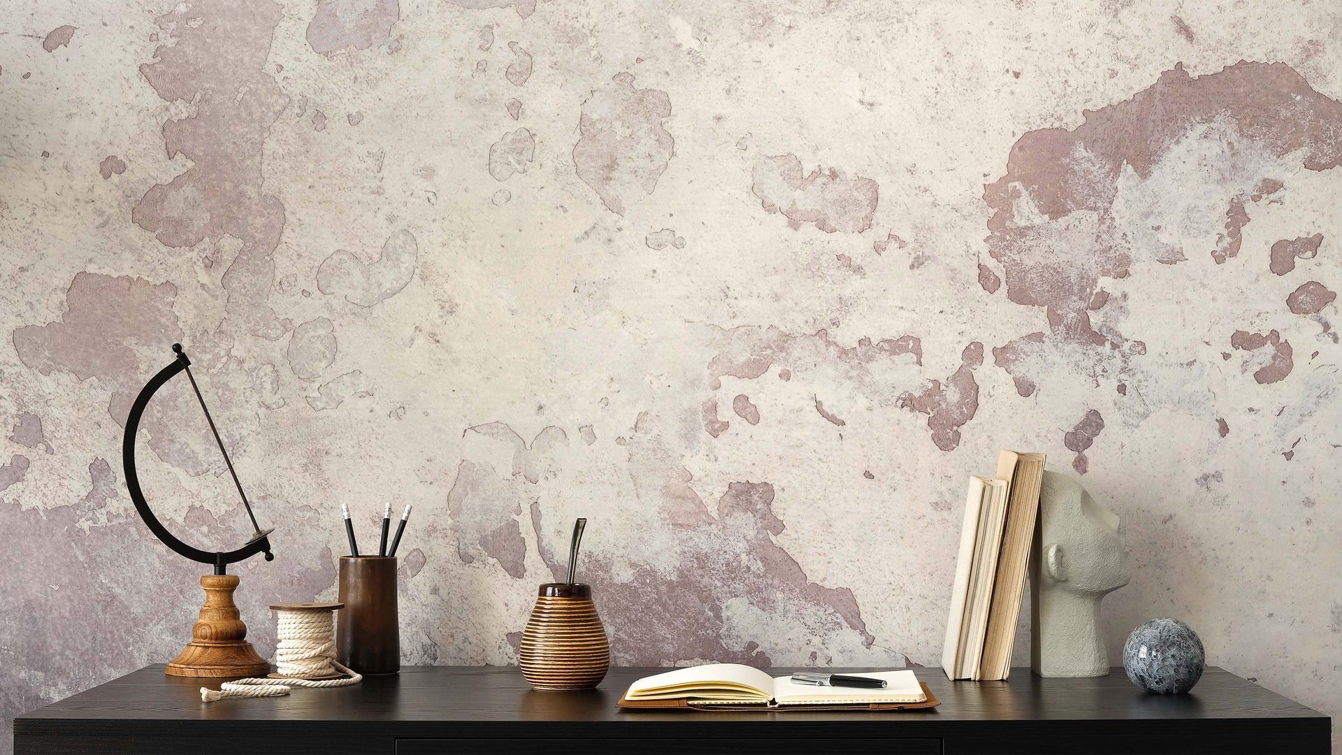 Desk with globe, books, and stationery against textured plaster wall with distressed paint finish