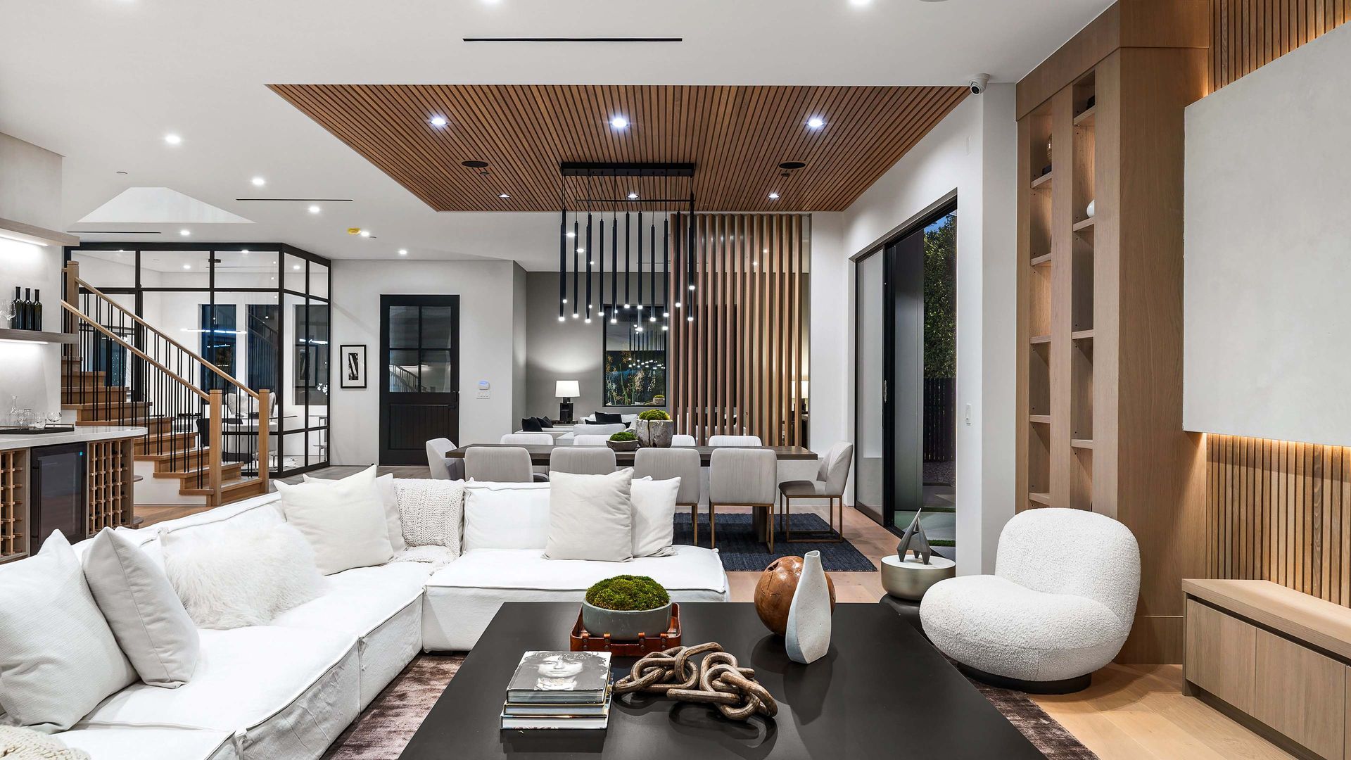 Modern living room with white sectional, wooden ceiling, and dining area.
