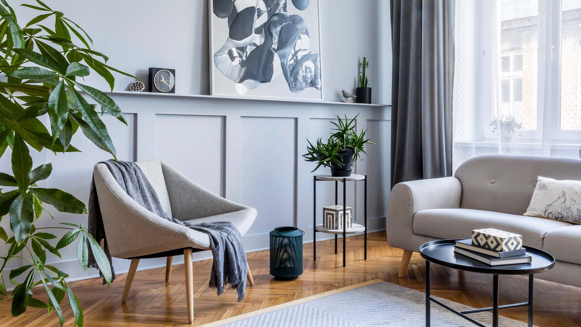 Living room with a gray and white color scheme, featuring a couch, chair, coffee table, and plants.