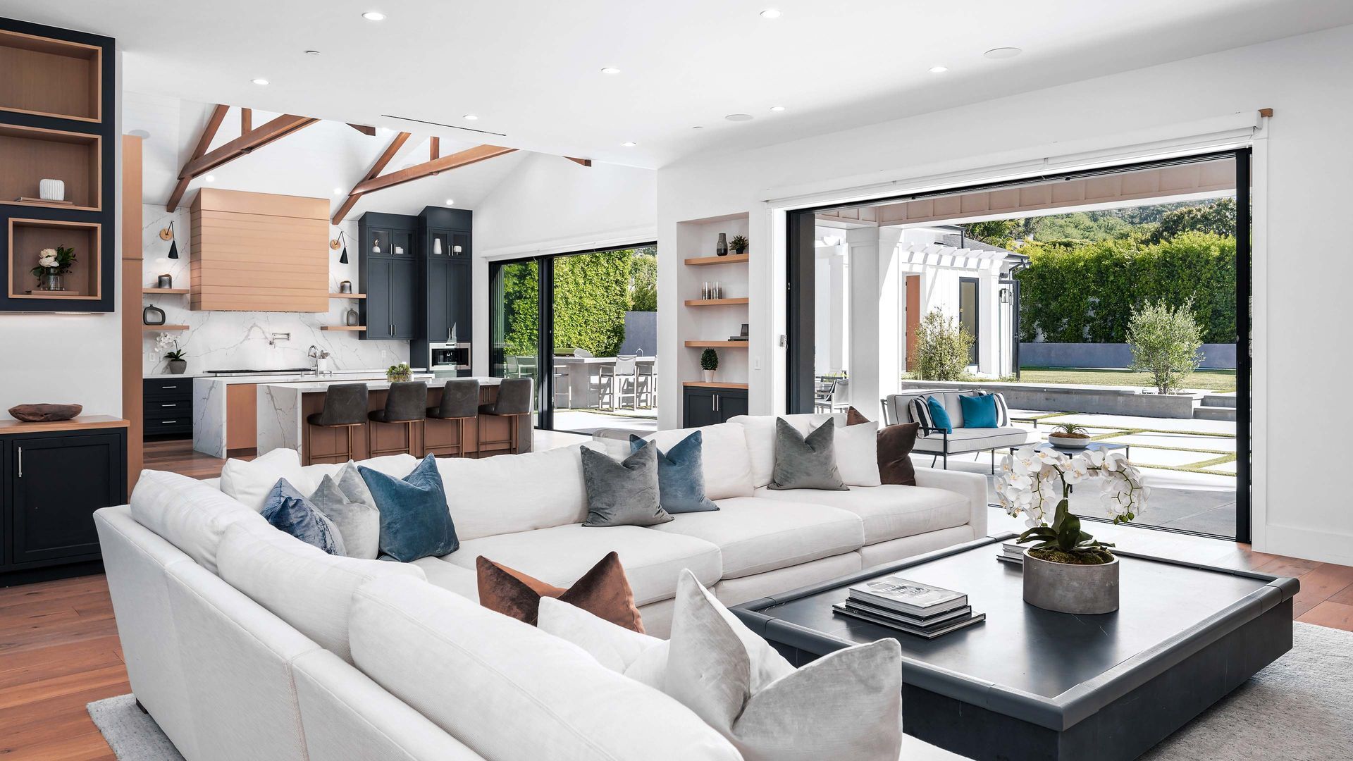 Modern open-concept living room with white sectional, kitchen, and sliding doors to a patio.