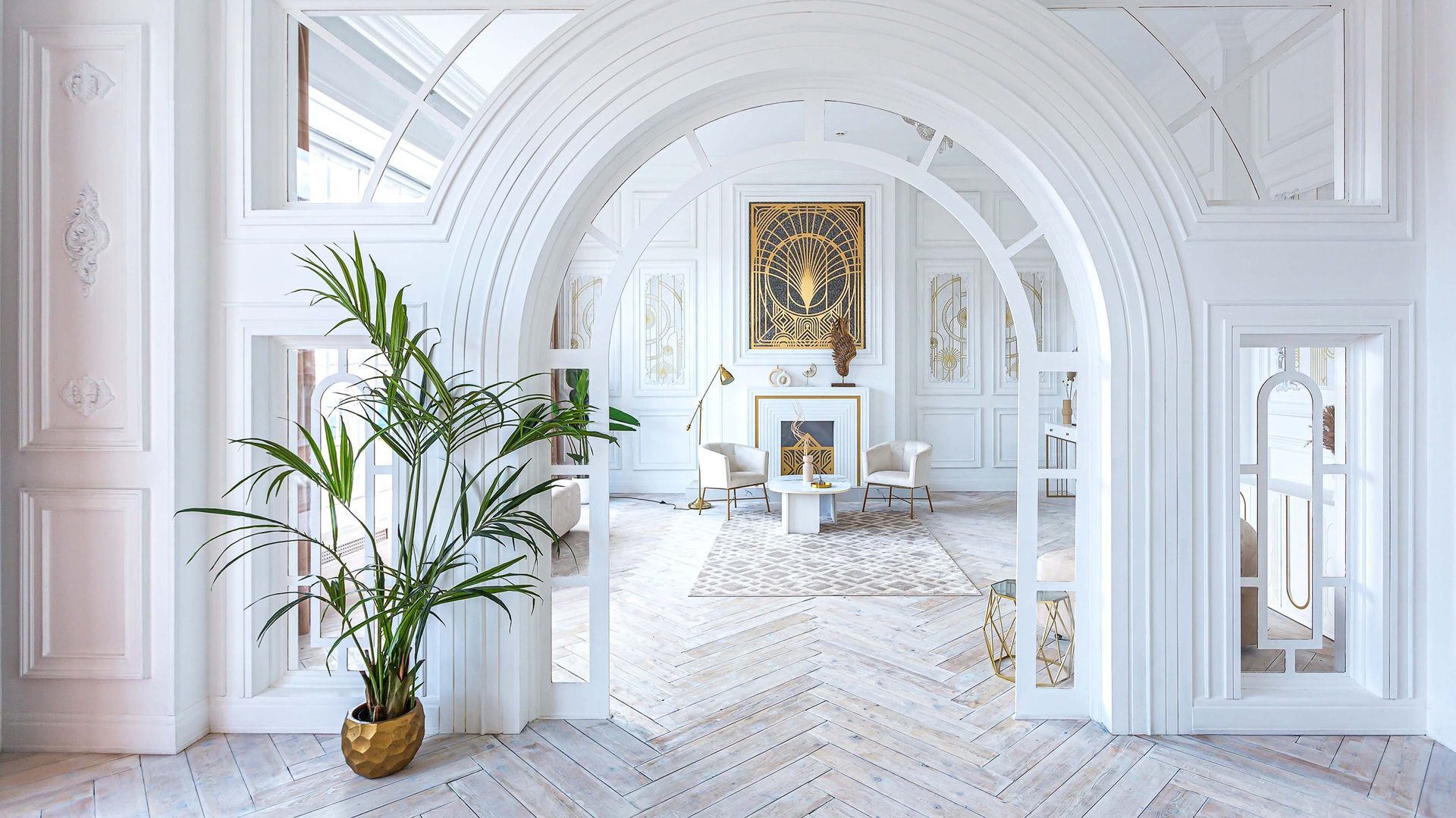 Ornate, white interior with arched doorways. A large plant in a gold pot is in the foreground.