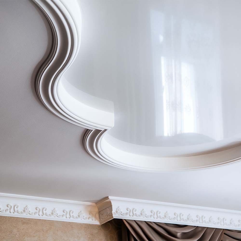 White decorative ceiling with ornate molding and reflective glossy surface.