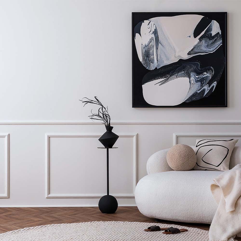 Modern living room with black and white abstract art, a white sofa, and decorative vase.