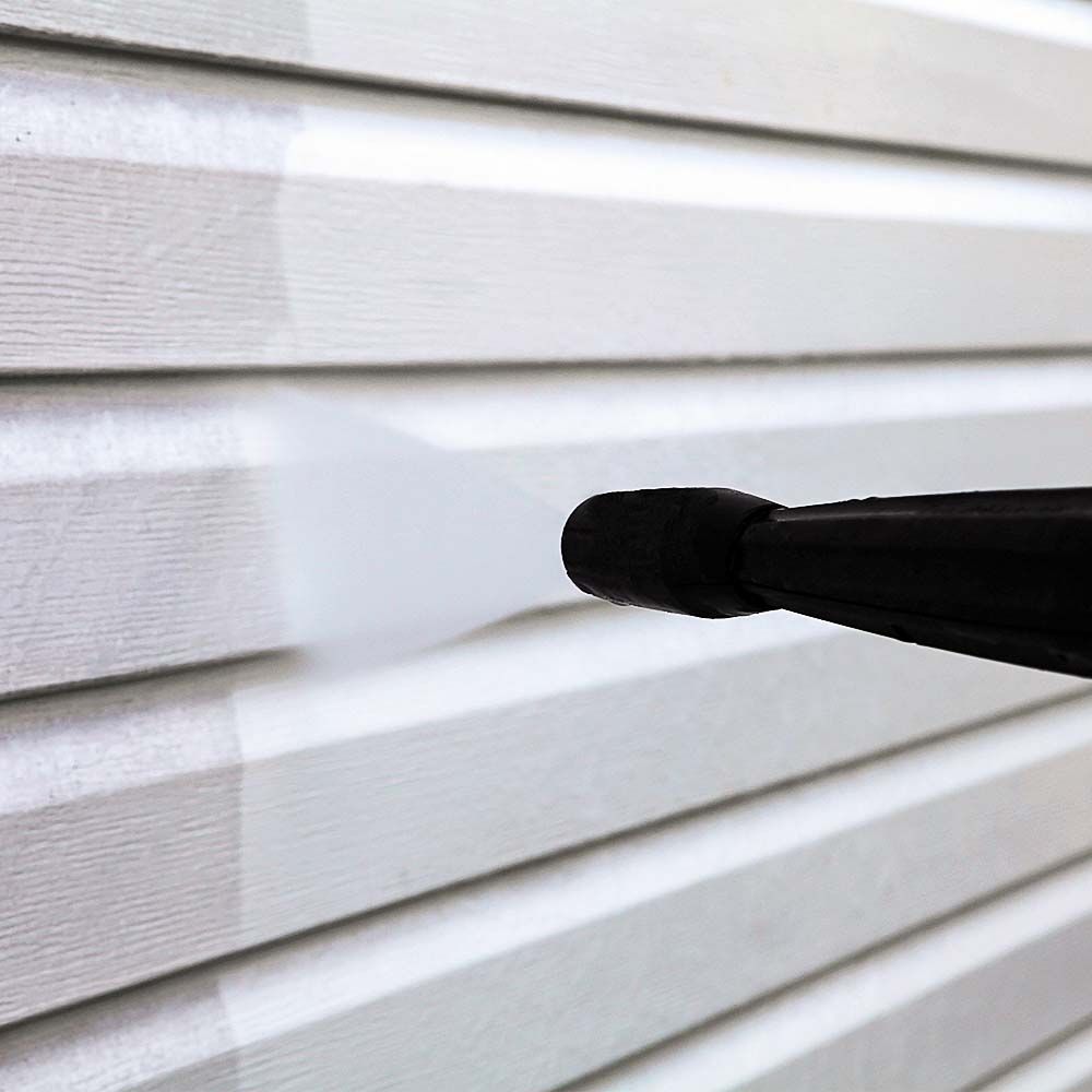 Power washer cleaning white vinyl siding.