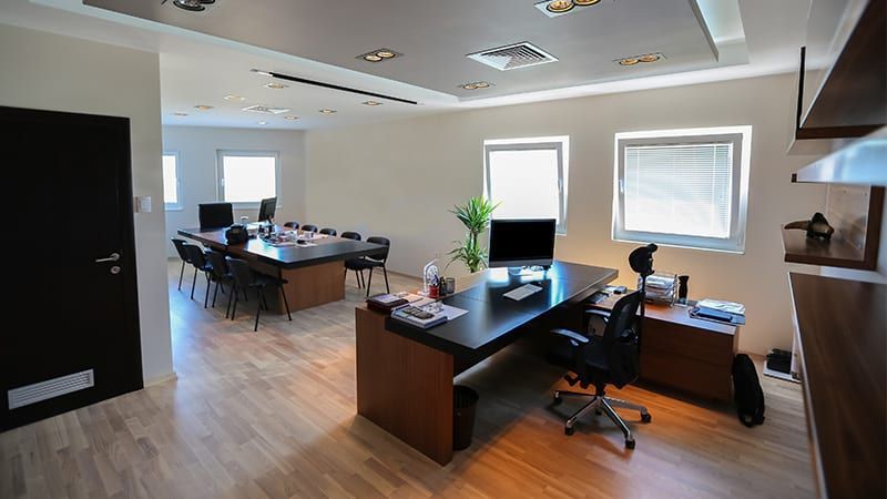 Modern office interior with a desk, conference table, and windows.