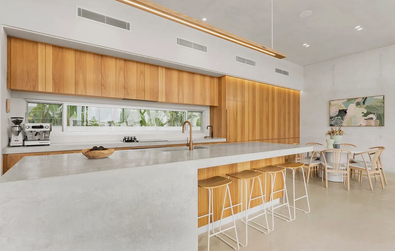 Modern kitchen with wood cabinetry, white countertops, and seating at the island — Maken Kitchens & Cabinets in Chinderah, NSW