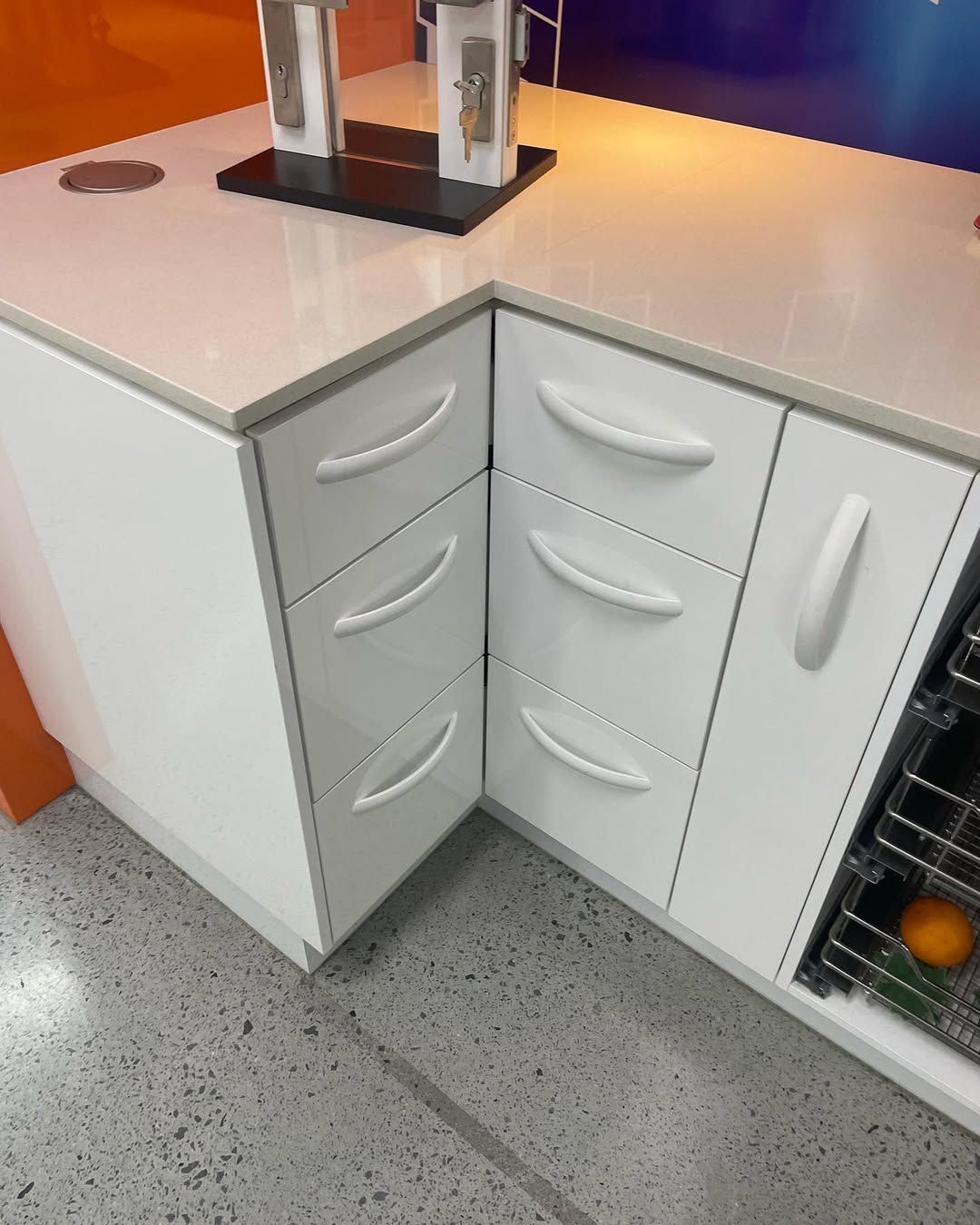 White kitchen cabinets with curved handles and countertop.  A corner cabinet has drawers. — Maken Kitchens & Cabinets in Pottsville, NSW