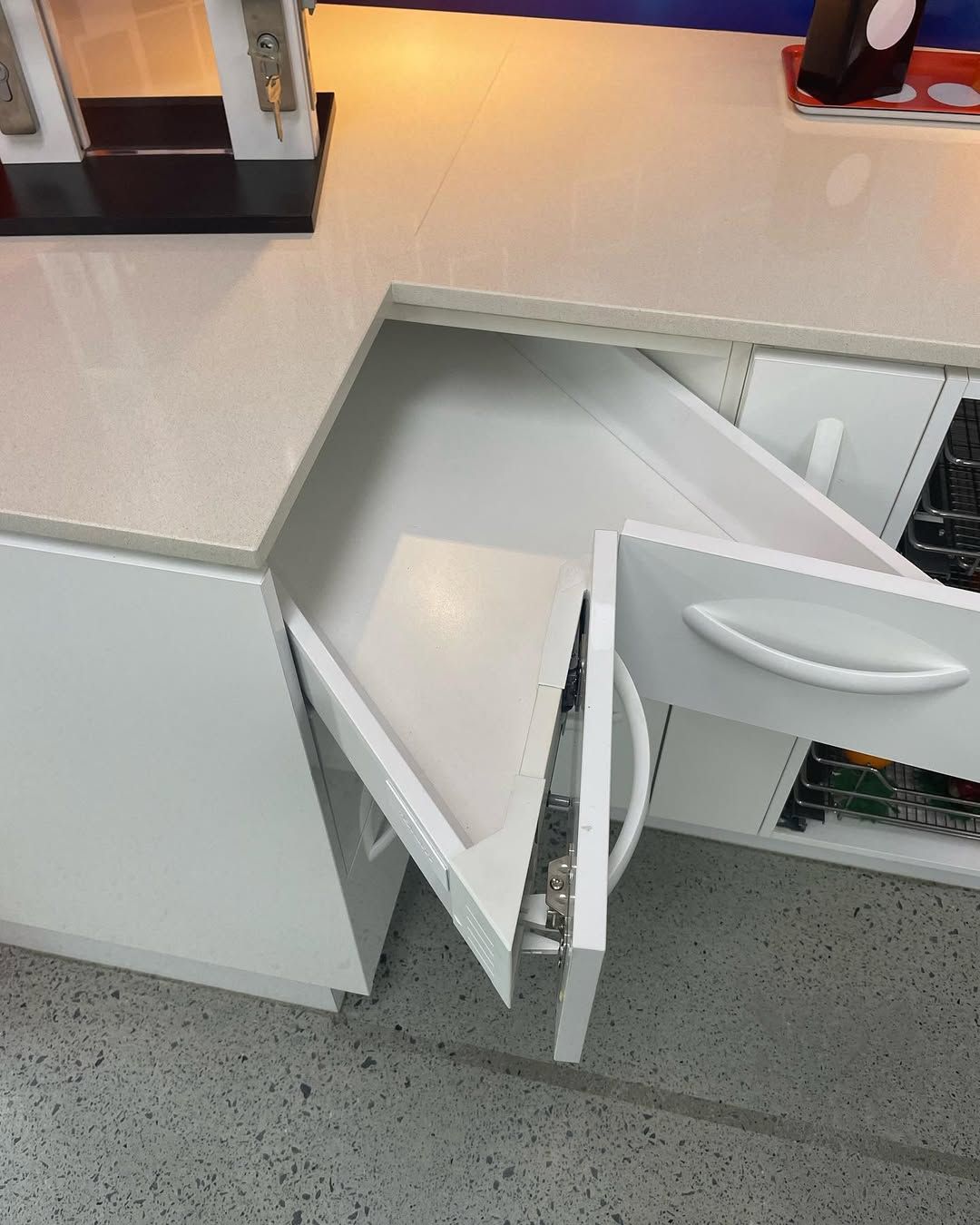 White corner kitchen cabinet with open, angled drawer. Countertop, white cabinets — Maken Kitchens & Cabinets in Chinderah, NSW