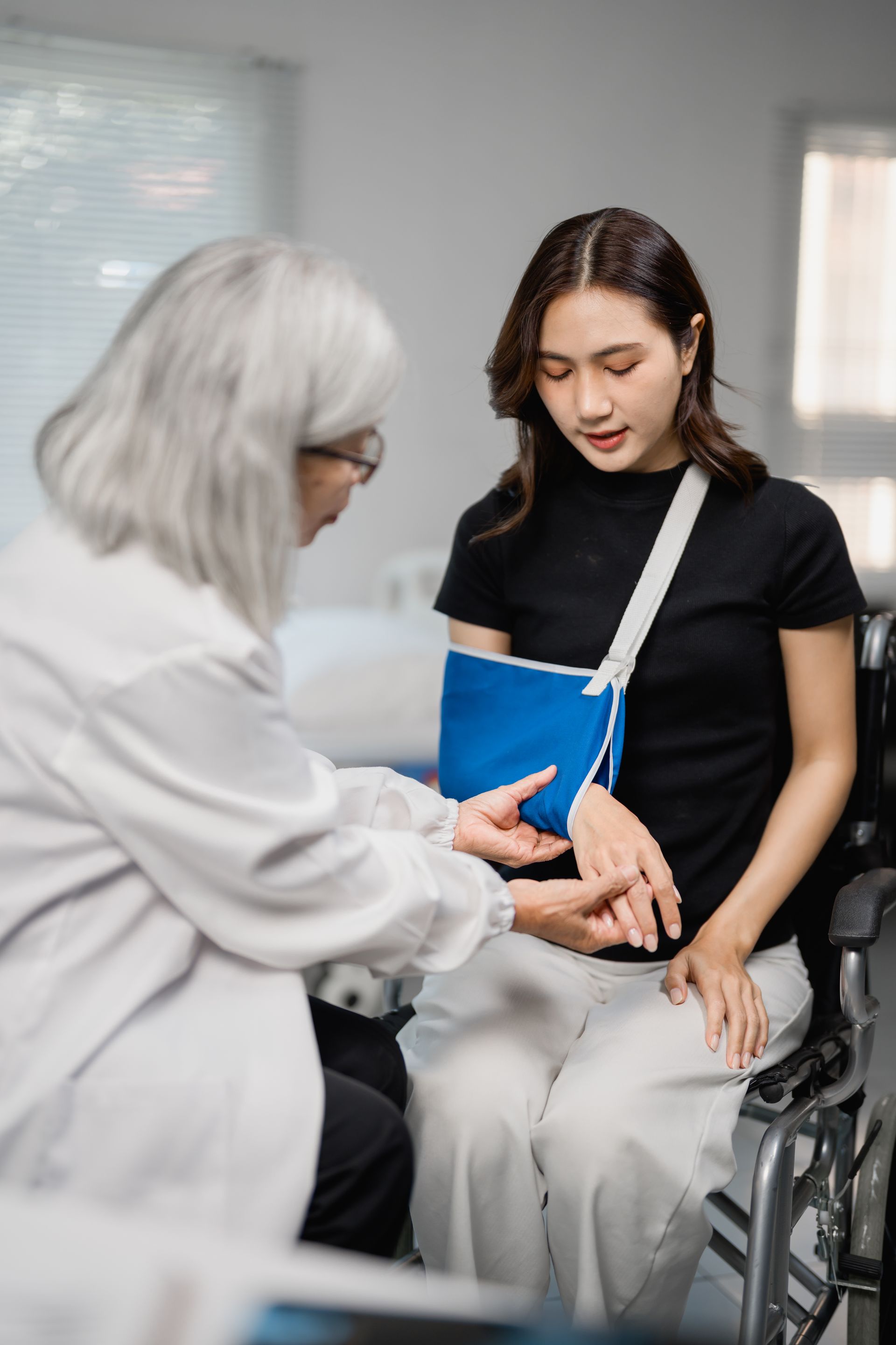 Doctor examining patient's injured arm in arm sling. Doctor examining patient's injured arm in arm sling.