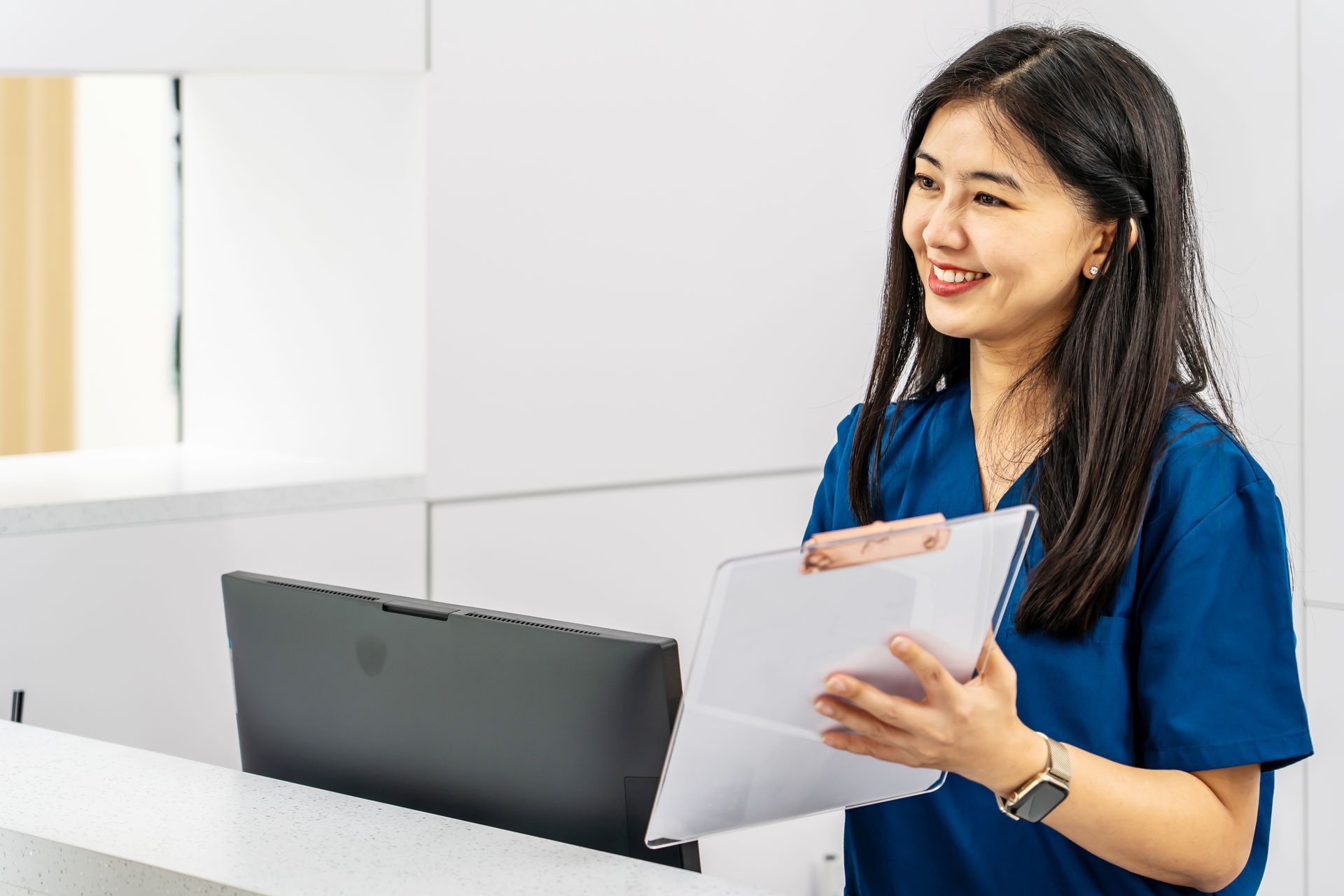 Adult woman stands near reception desk in clinic lobby area, asks information, makes appointment with doctor. Adult woman stands near reception desk in clinic lobby area, asks information, makes appointment with doctor.