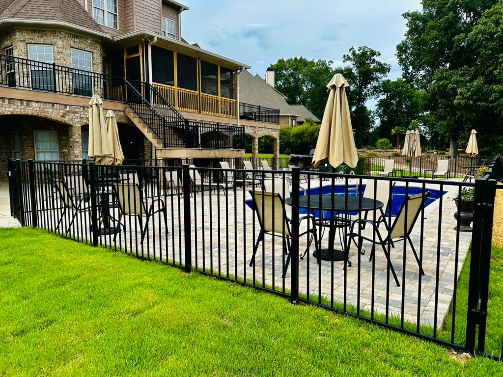 A fence surrounds a patio with tables and chairs and umbrellas.