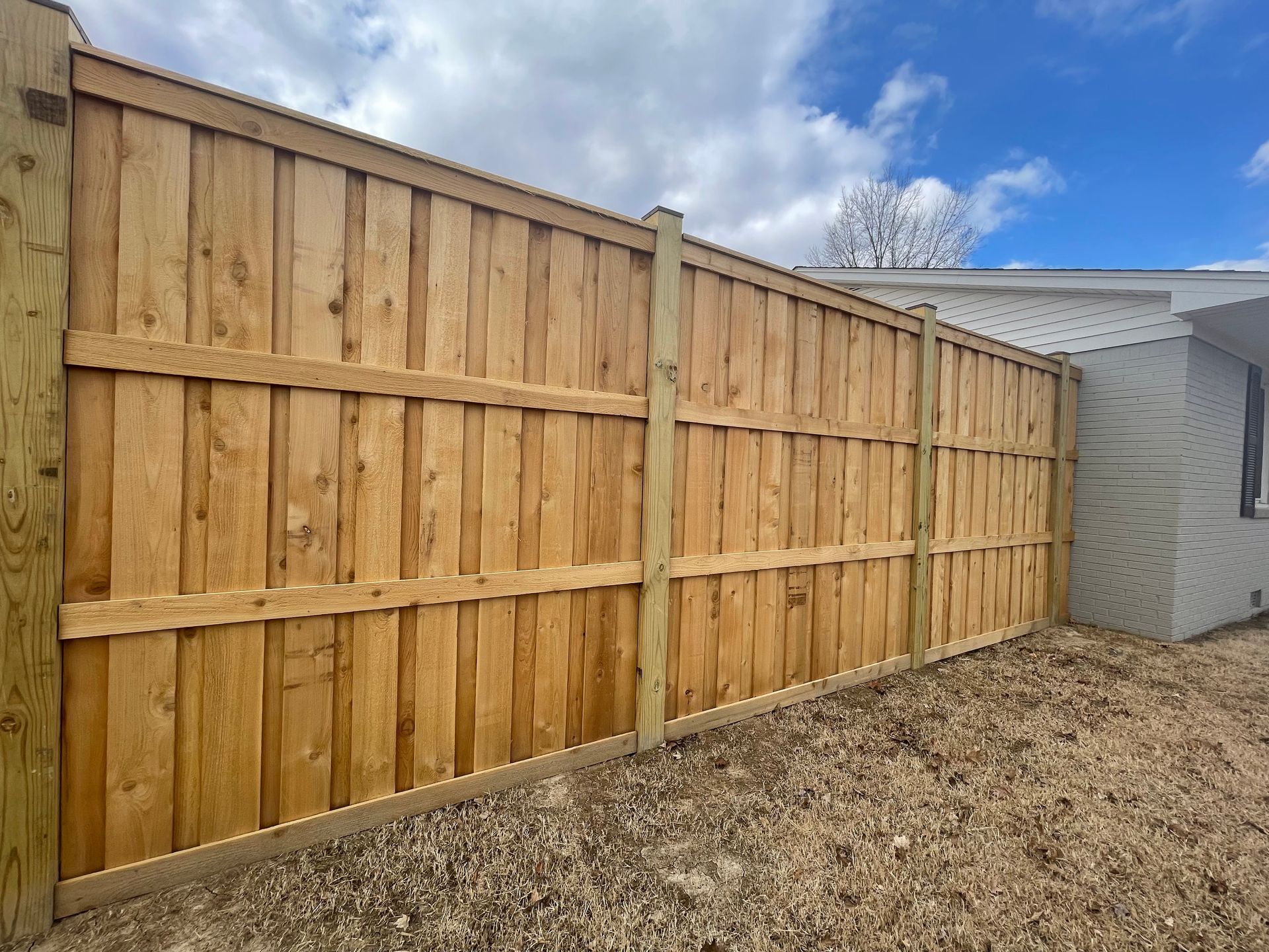 A wooden fence is in the backyard of a house.