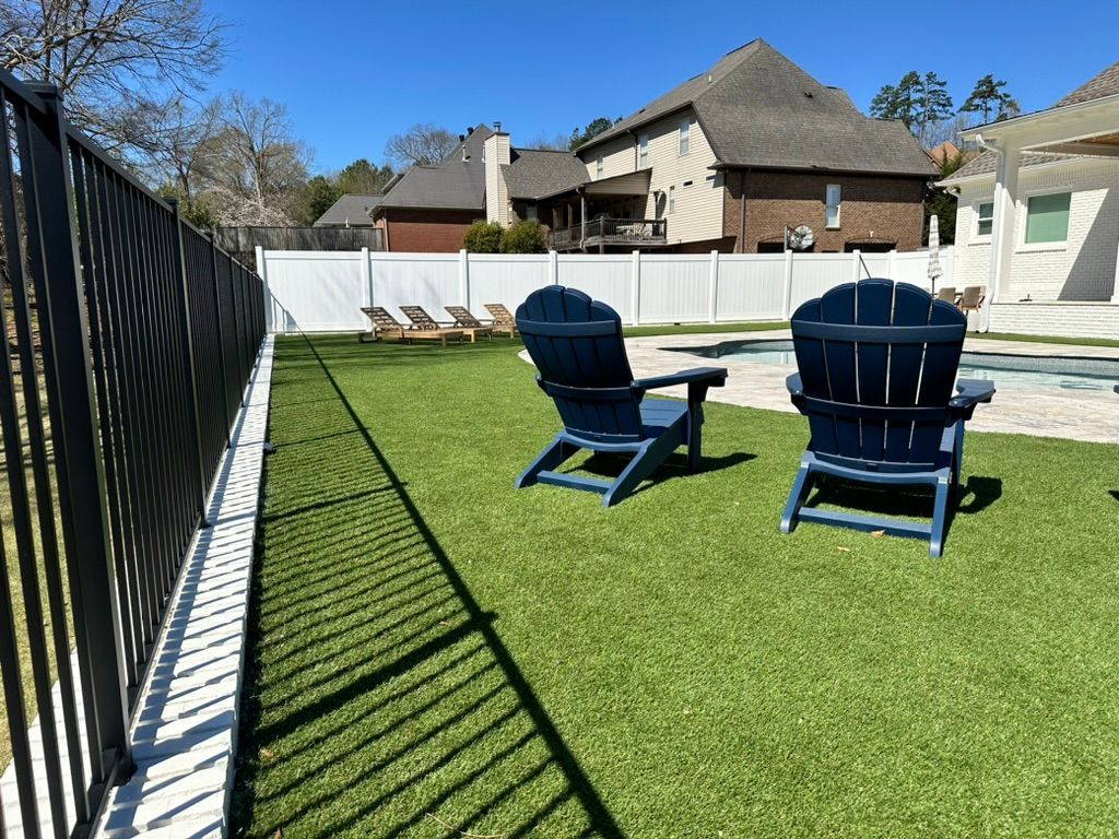 Two blue chairs are sitting on a lush green lawn next to a pool.