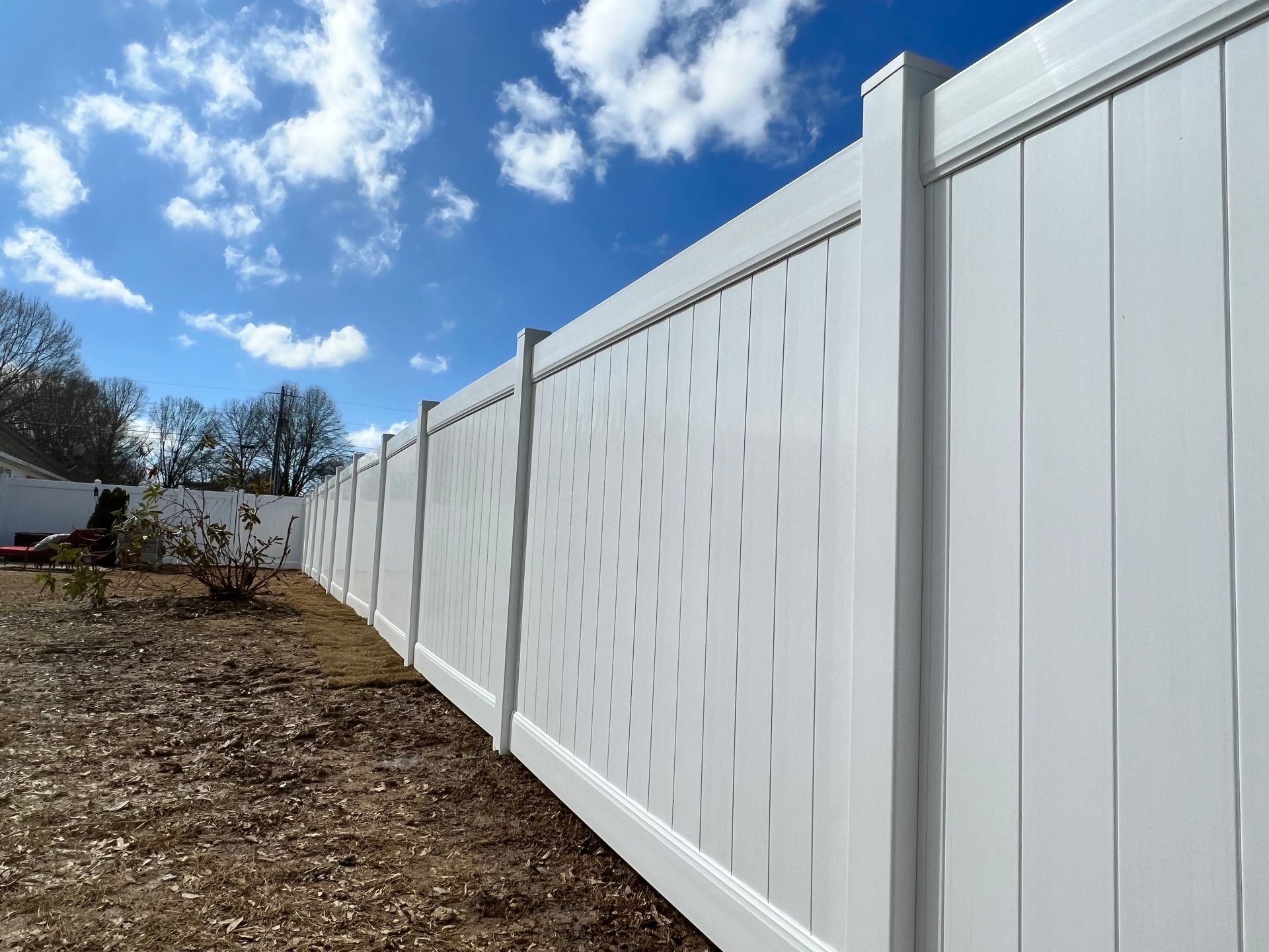 A white fence is sitting in the middle of a dirt field.