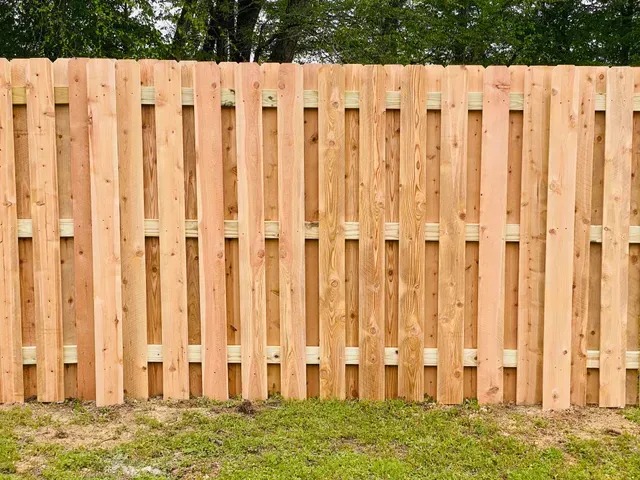 A wooden fence made of wooden boards is sitting on top of gravel.