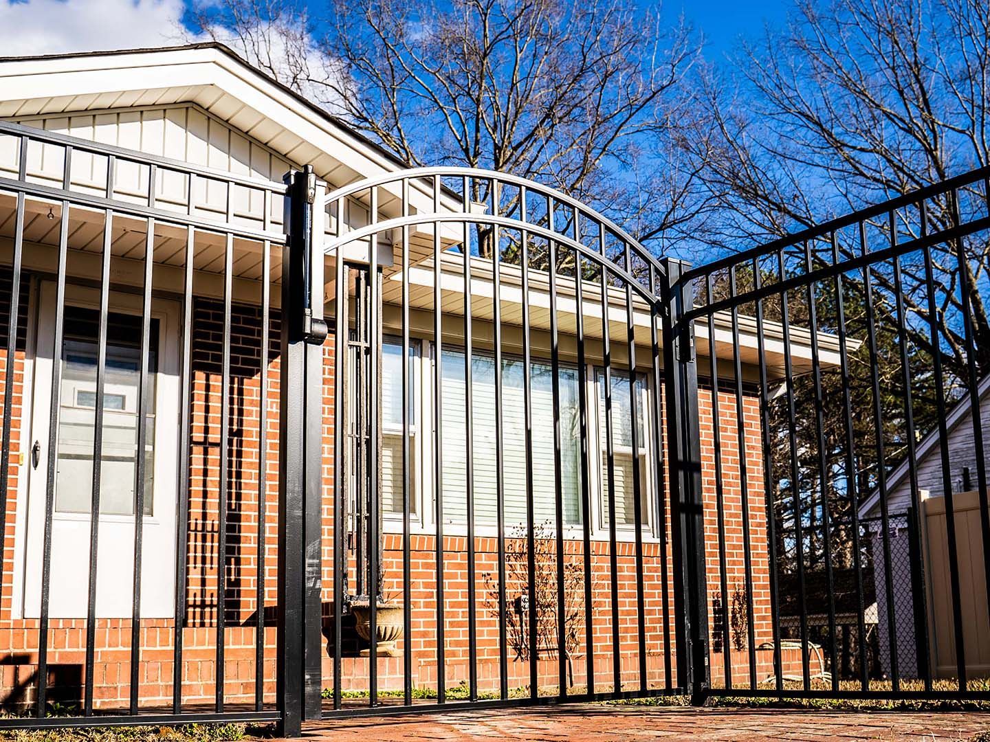 A brick house with a wrought iron gate in front of it.