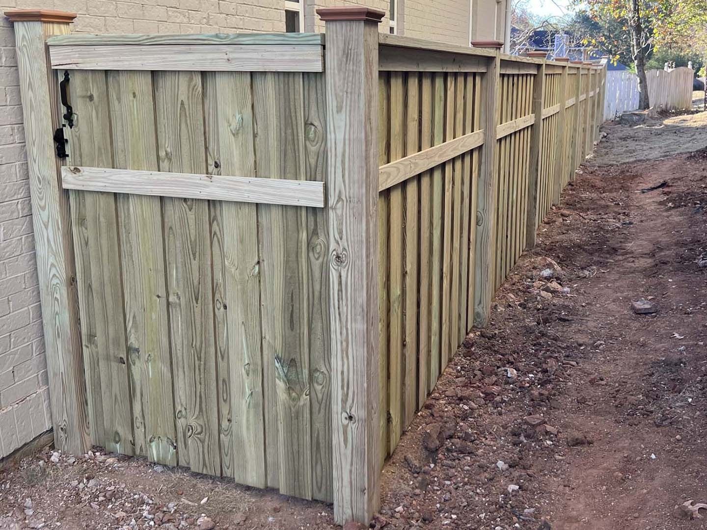 A wooden fence is sitting next to a dirt road.