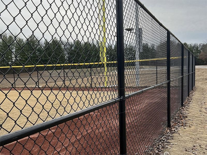A chain link fence surrounds a baseball field.