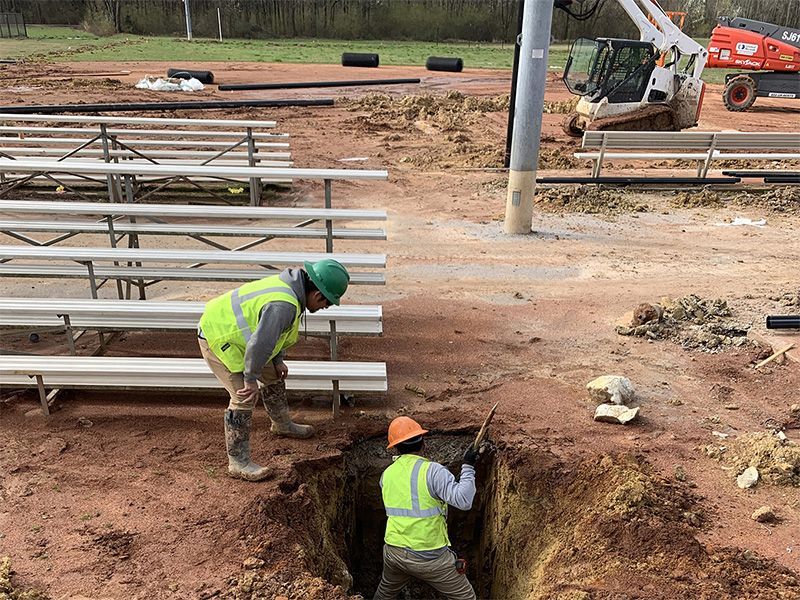 Two construction workers are digging a hole in the dirt.