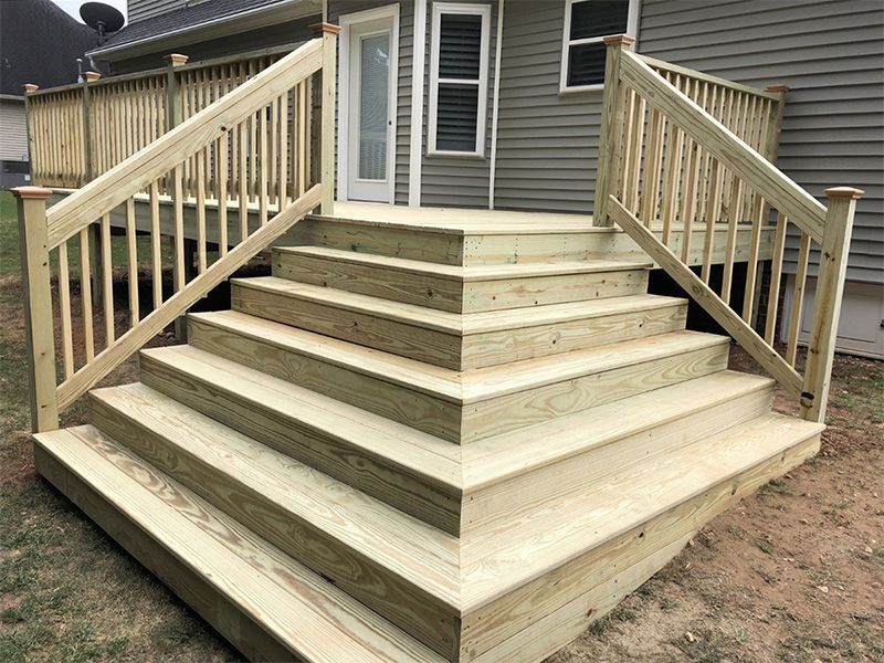 A wooden deck with stairs leading up to a house.