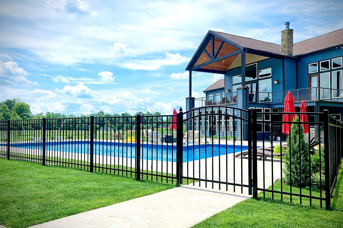 Black fenced-in pool with a light blue house in the background on a sunny day.